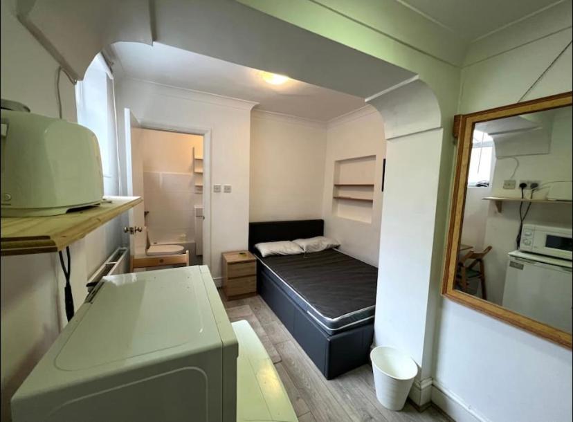 a small room with a bed and a mirror at En-suite near everything. Shepherd's Bush - London in London