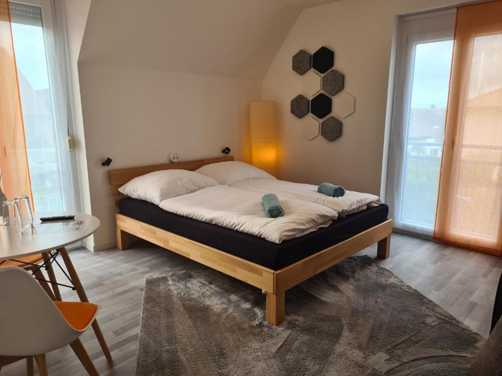 een slaapkamer met een bed en een tafel en ramen bij Lichtdurchflutetes Zimmer - Mainwiesen in Waldbüttelbrunn