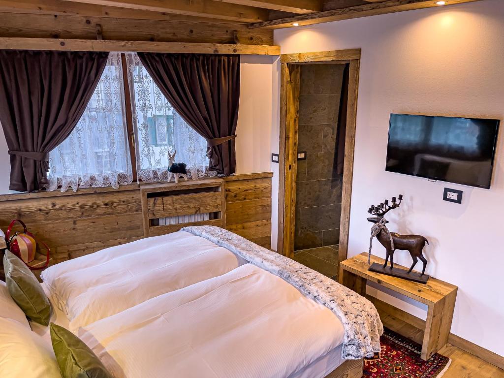 a bedroom with a bed and a flat screen tv at Hotel da Beppe Sello in Cortina dʼAmpezzo