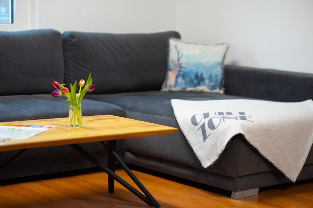 eine schwarze Couch mit einem Tisch und eine Vase mit Blumen in der Unterkunft Garden Town Appartement in Salzburg