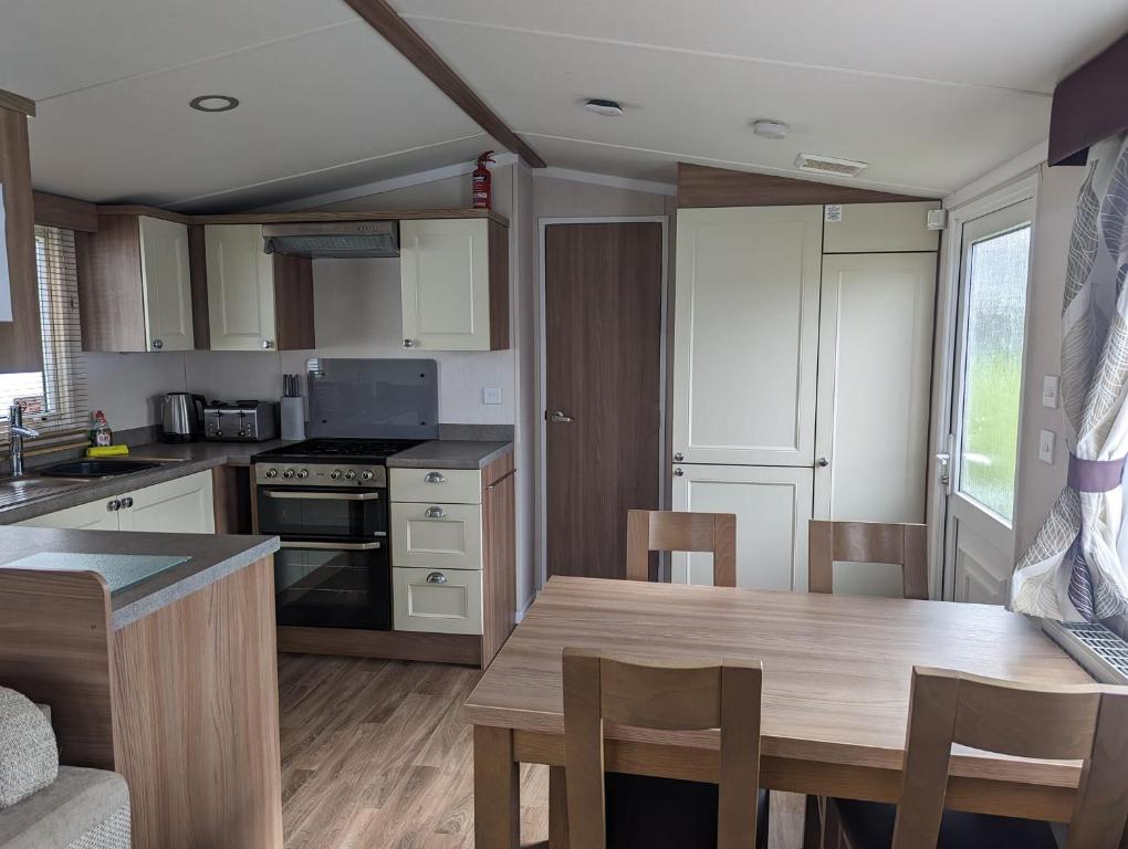 uma cozinha com uma mesa de madeira e uma sala de jantar em Swift holidays at Combe Haven Holiday Park em Hastings