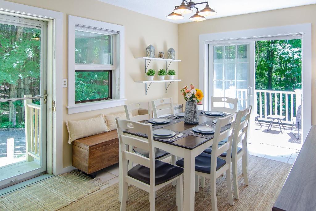 a dining room with a table and chairs and windows at Bayley Way Getaway in White River Junction