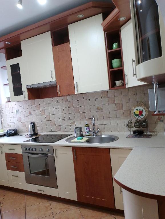 a kitchen with a sink and a stove at Mieszkanie Jadwigi in Giżycko