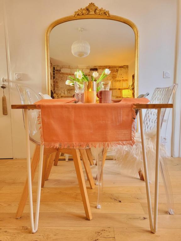 einen Tisch vor einem Spiegel mit Blumen darauf in der Unterkunft -Parking privé -La BATISSE -Coeur historique - La Clef de Honfleur in Honfleur