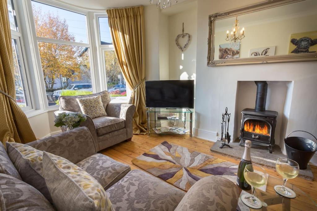 sala de estar con sofá y chimenea en Holly Cottage, en Bowness-on-Windermere