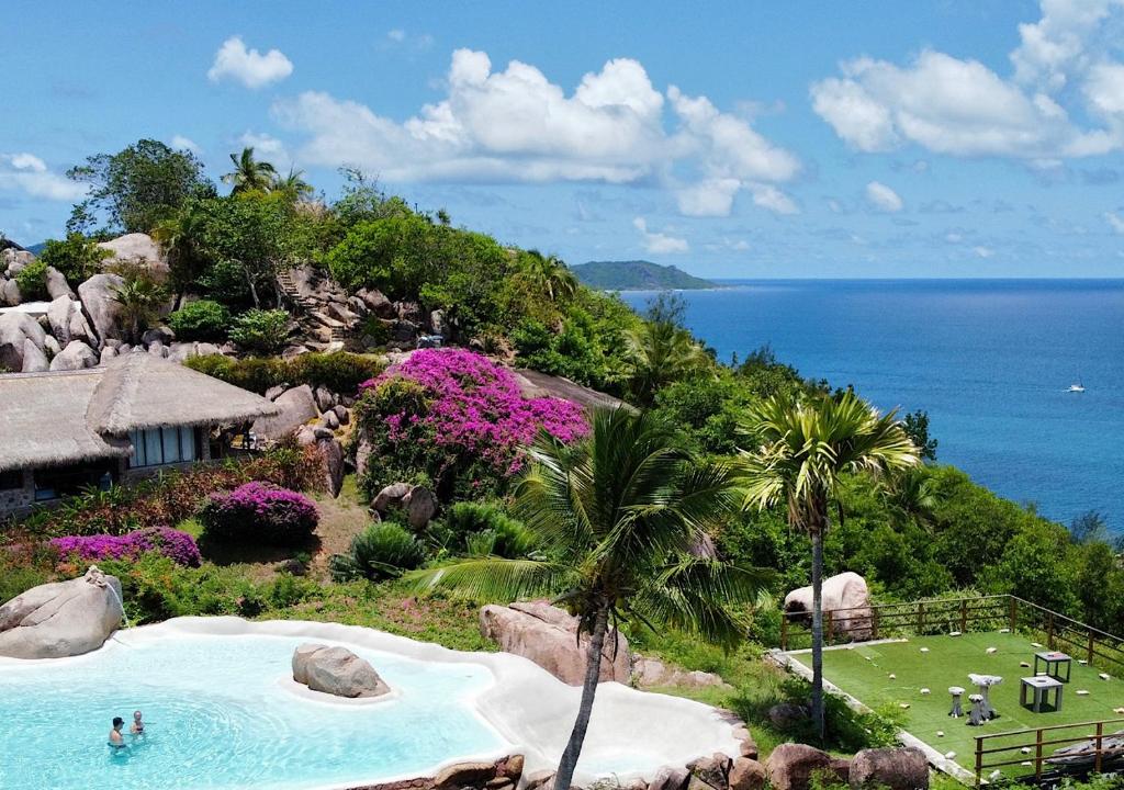 a resort swimming pool with a view of the ocean at Château de feuilles in Baie Sainte Anne