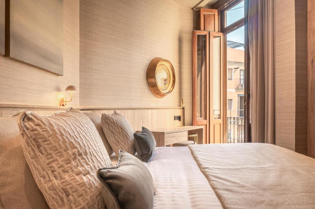 um quarto com uma cama com almofadas e uma janela em The Valentia Corretgería em Valência