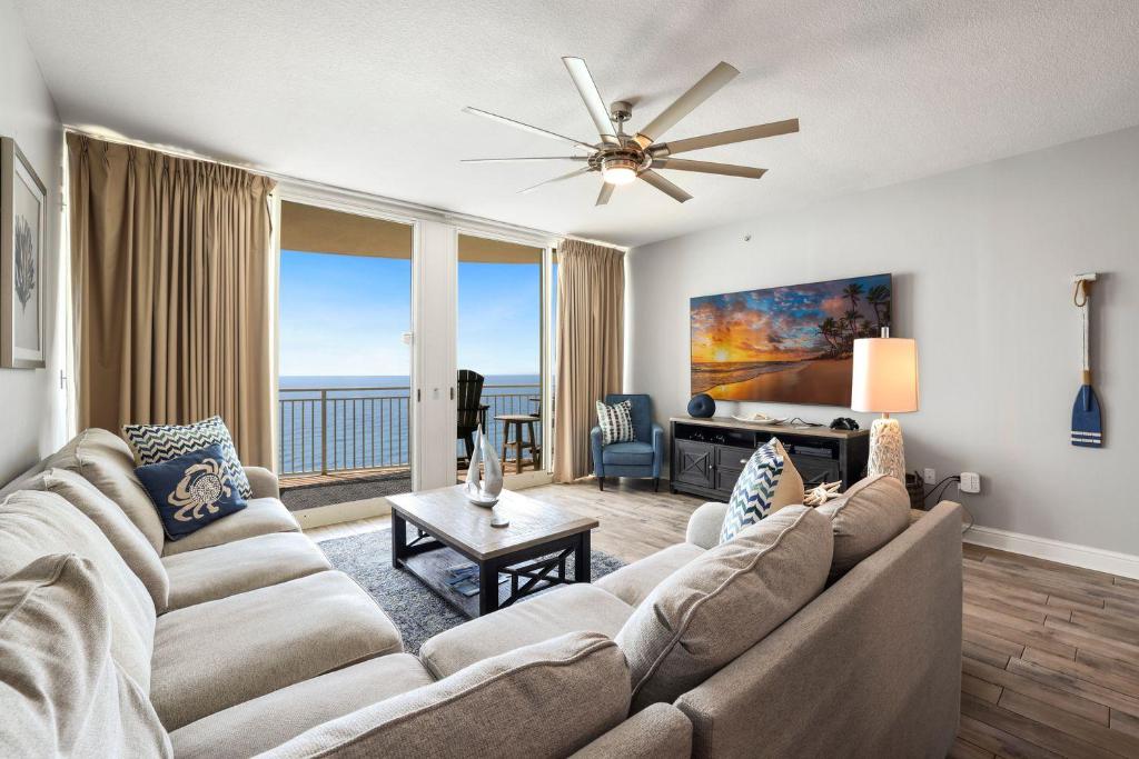 a living room with a large couch and a large window at Totally Beach'n at 1605 Aqua in Panama City Beach