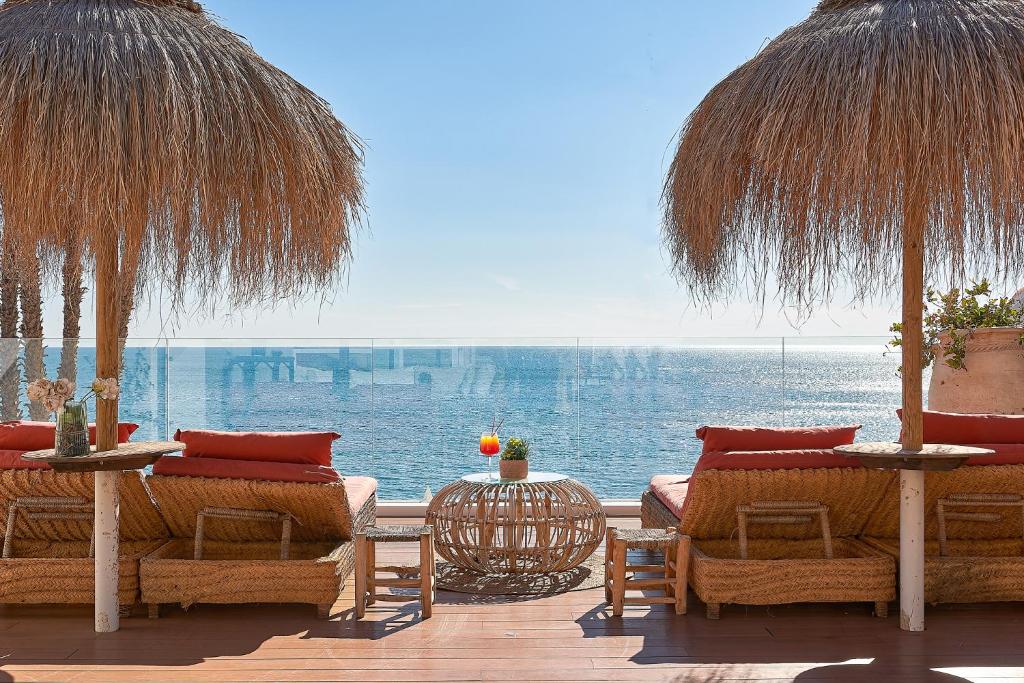 a patio with chairs and tables and a view of the water at Suite Deluxe Face Mer Apart Malaga in Málaga