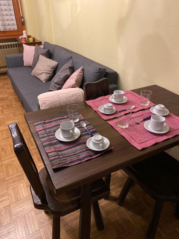 uma mesa de madeira com pratos e copos com um sofá em BeSt Volpe em Sestriere