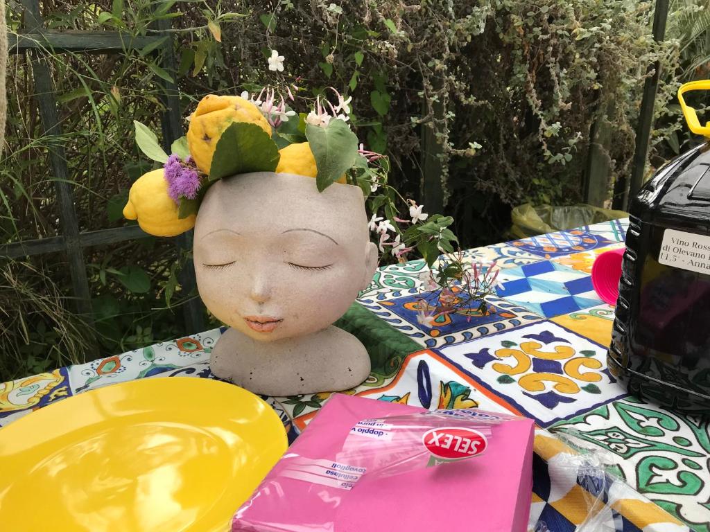una muñeca con una corona de flores en la cabeza sobre una mesa en La Gallina Felice B&B, en Meta