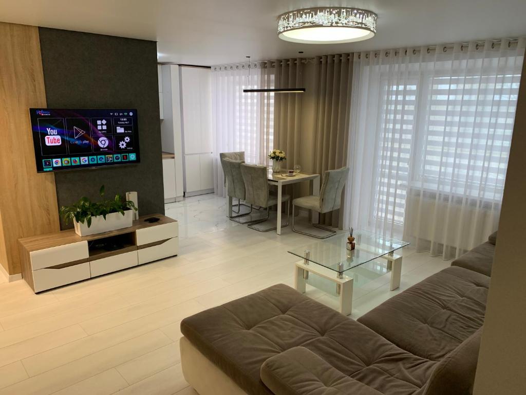 ein Wohnzimmer mit einem Sofa und einem Tisch mit einem TV in der Unterkunft Апартаменты LUXURY in Berdychiv