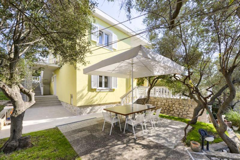 a table and chairs with an umbrella in front of a house at APARTMAN MARICA LUN, OTOK PAG in Lun