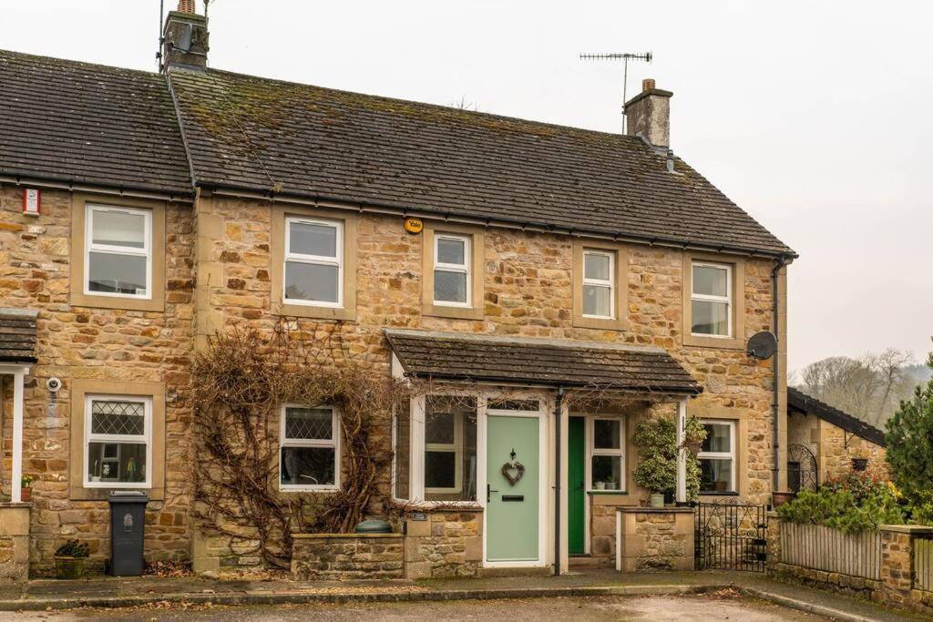 una vieja casa de ladrillo con una puerta verde en Barley Cottage, en Whittington