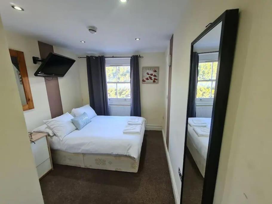 um pequeno quarto com uma cama e um espelho em Lovely bedroom em Londres