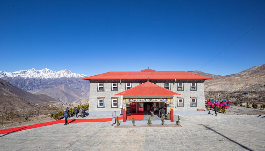 a large building with a red roof with people standing around it at Lo Mustang Himalayan Resort in Muktināth