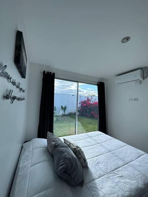 a bedroom with a bed with a large window at Casa a 4km del aeropuerto SJO in Santiago Este
