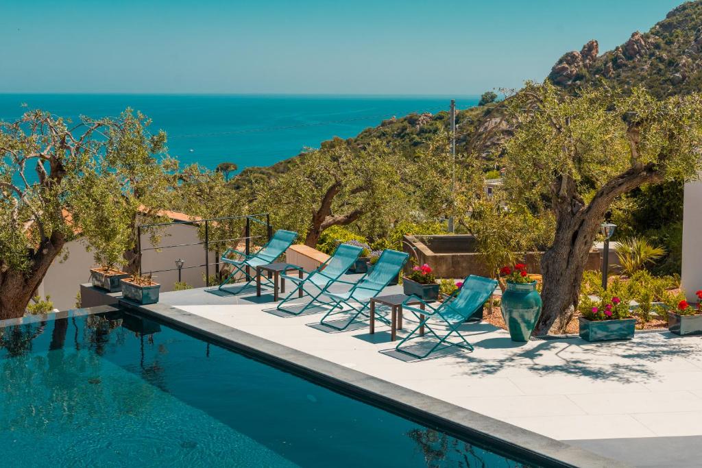 a pool with chairs and the ocean in the background at Villa Totò Resort in Cefalù