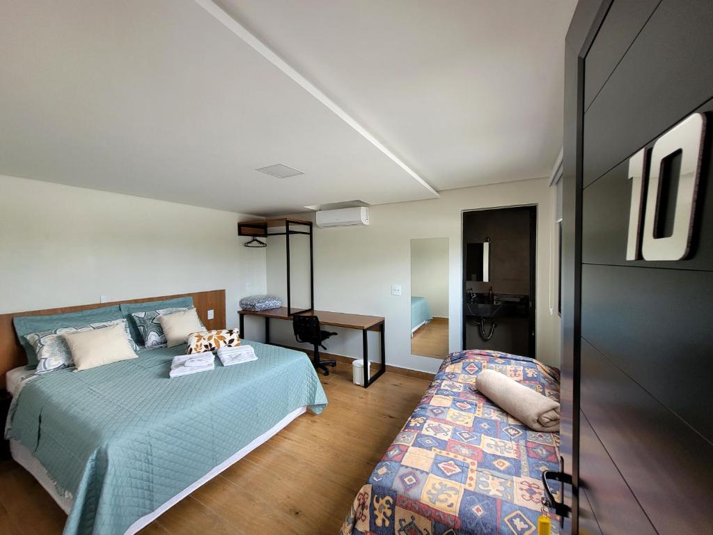 a bedroom with a bed and a desk and a table at Pousada Jardim do Lago in Cascavel
