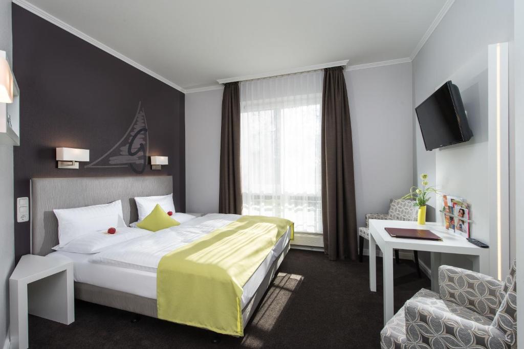 
a hotel room with a bed, desk, and a lamp at Hotel Godewind in Warnemünde
