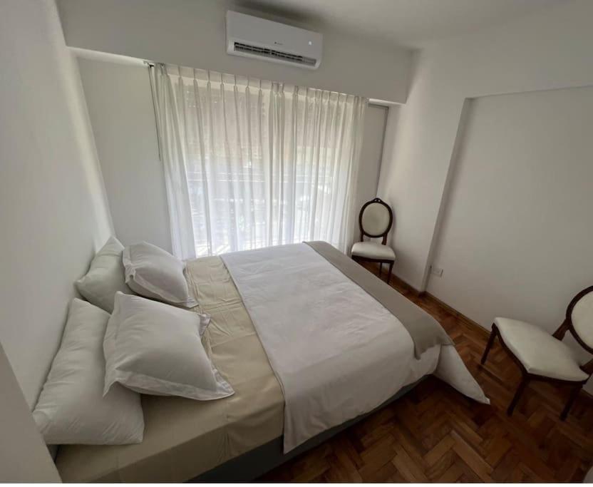 1 dormitorio con 1 cama con sábanas blancas y ventana en Amigable departamento en palermo en Buenos Aires