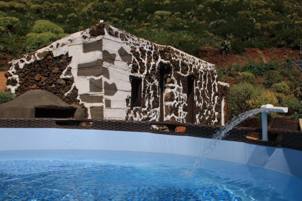 un edificio de piedra con una fuente en una piscina en La Chusmita en Valverde
