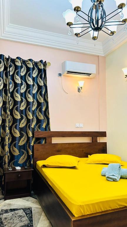 a bedroom with a yellow bed and a chandelier at Chambre meublée Biyem Assi TKC in Yaoundé