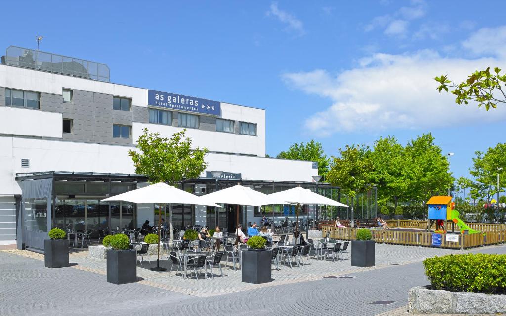 a group of tables and chairs with umbrellas in front of a building at Aparthotel Attica21 As Galeras in Bastiagueiro