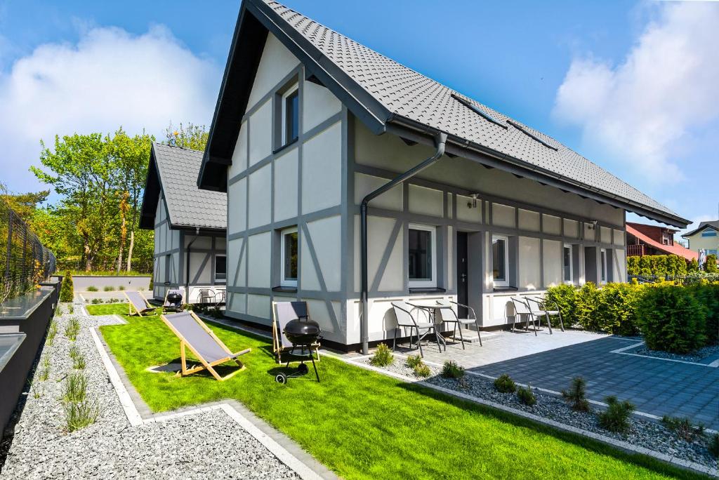 ein Haus mit einem Garten und einer Terrasse in der Unterkunft Domki Apartamentowe - Na Makowej in Jastrzębia Góra