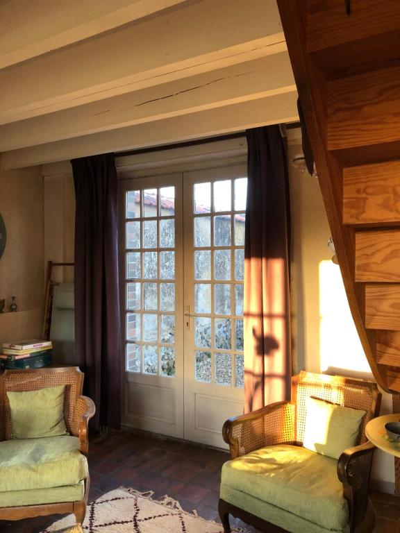 salon z 2 krzesłami i drzwiami w obiekcie Sainte-Suzanne gîte de LA FERME calme et tranquille w mieście Les Baux-de-Breteuil