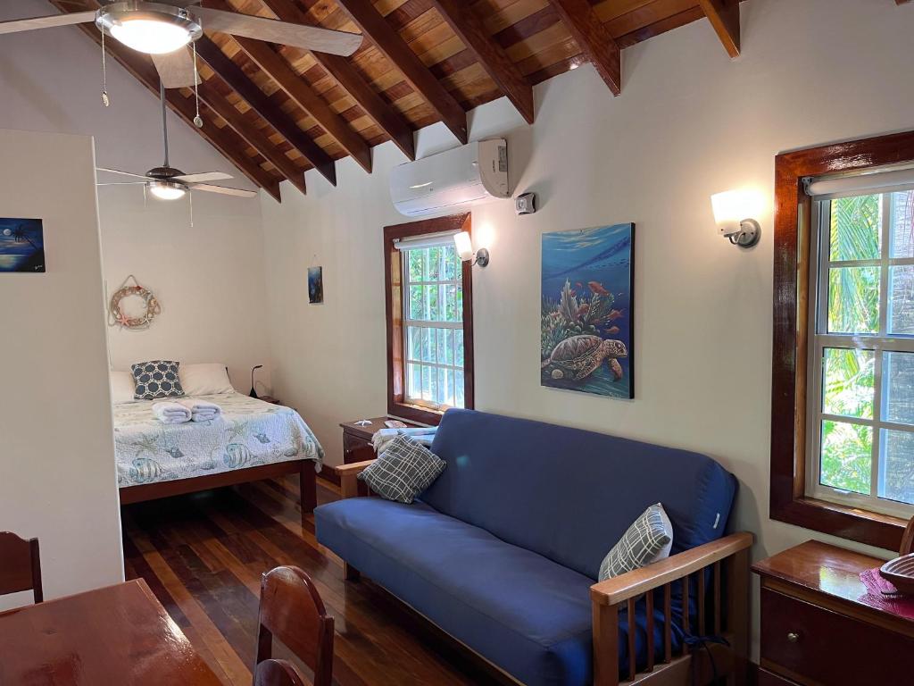 a living room with a blue couch and a bed at Sea Garden Cottage in Caye Caulker