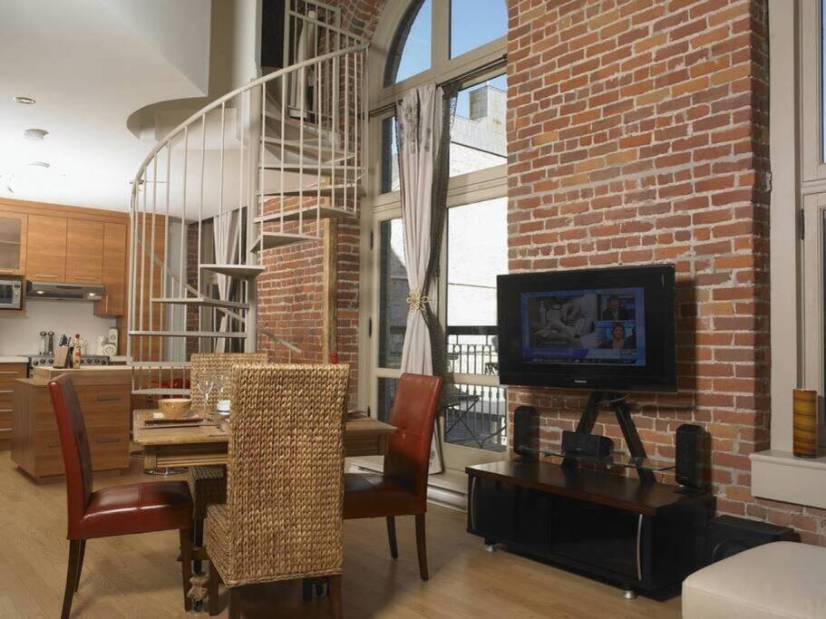 a living room with a dining table and a brick wall at Loft au coeur du Vieux-Québec in Quebec City
