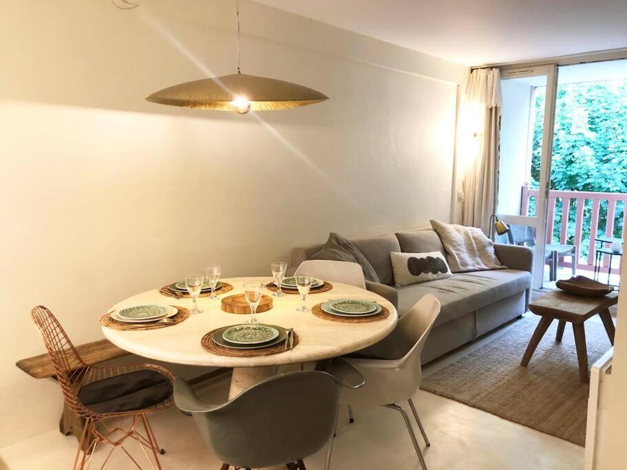 a living room with a table and a couch at Appartement 2 chambres COULEUR DUNE, piscine, parking gratuit in Le Touquet-Paris-Plage