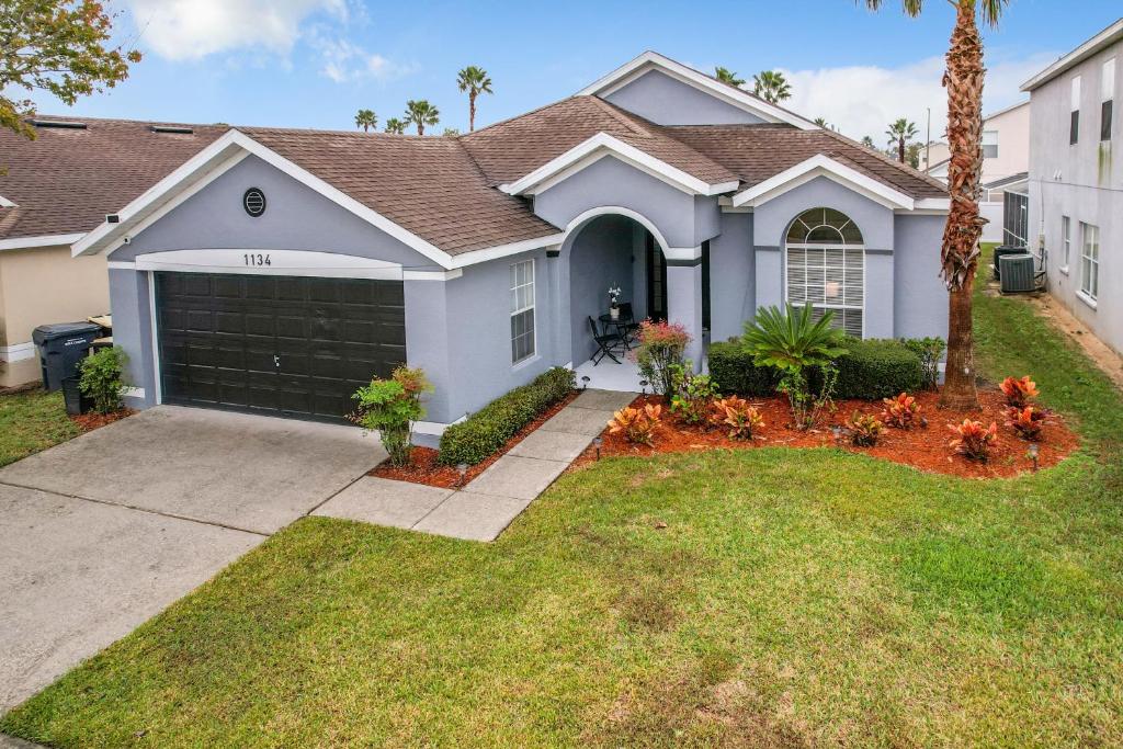 a house with a garage and a palm tree at Gorgeous Pool Home Near Disney - 2024 specials! in Davenport