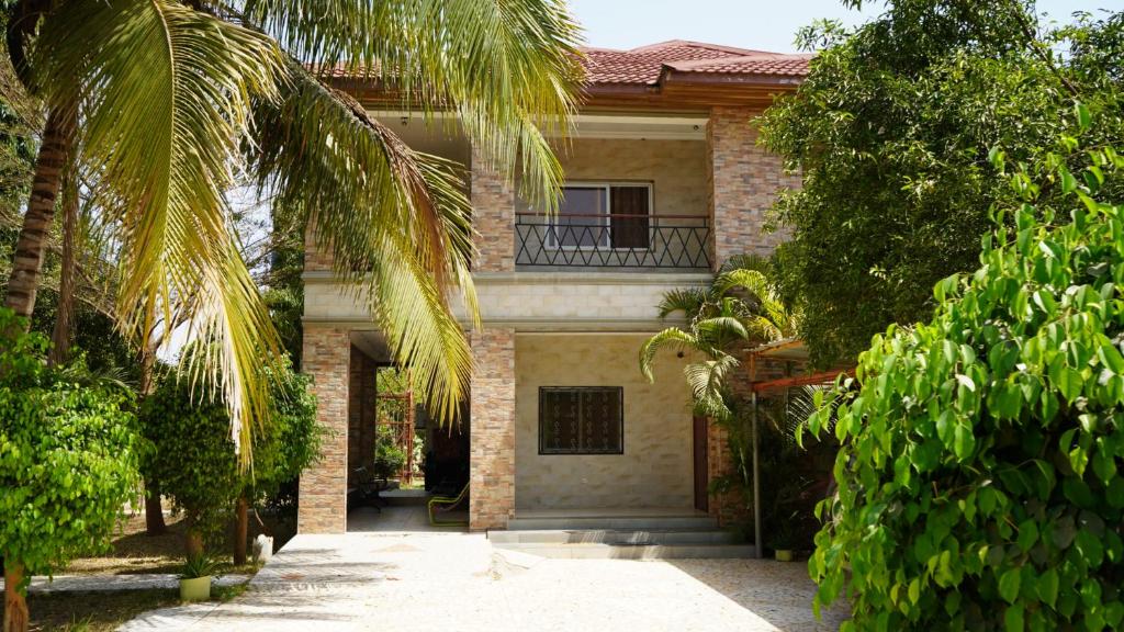 a house with a palm tree in front of it at Maajob Resort in Brikama