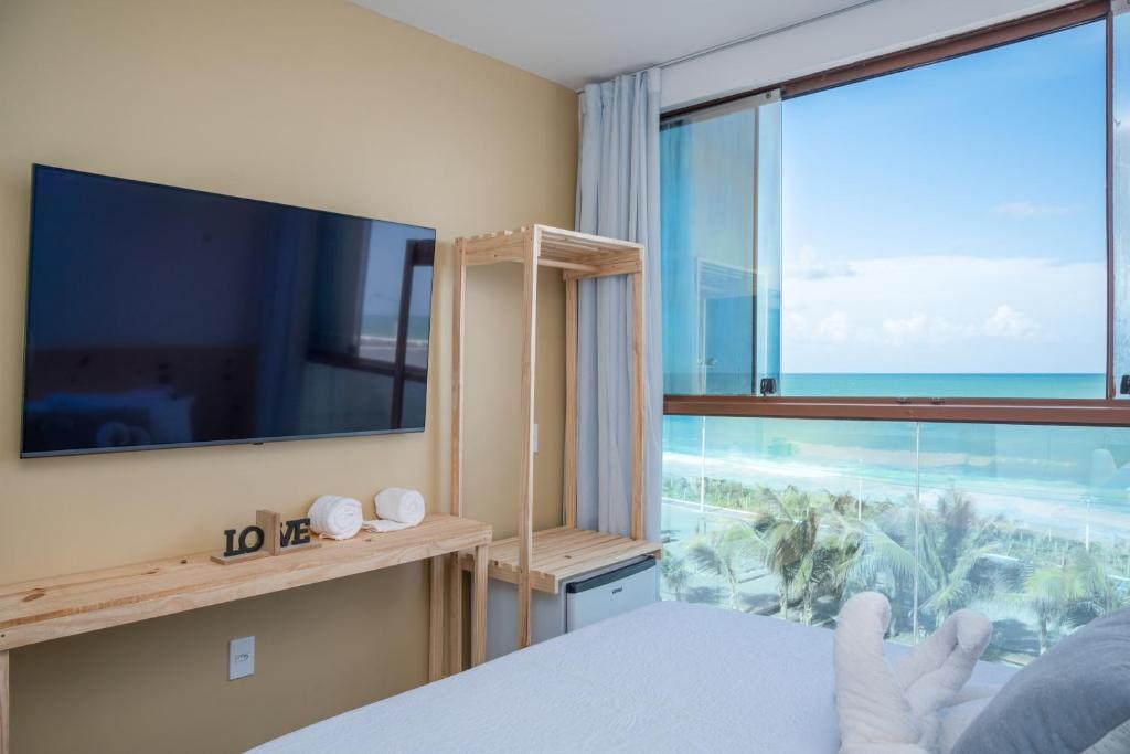a bedroom with a large window with a view of the ocean at Hotel Pousada Aloha in Maceió