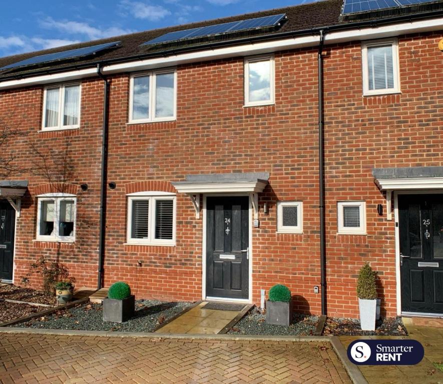 une maison en briques rouges avec portes et fenêtres noires dans l'établissement High Wycombe - 2 Bedroom House, à Buckinghamshire