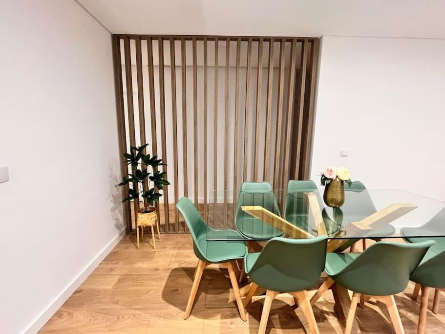 a dining room with a glass table and green chairs at Cunha's Apartment - city center in Guimarães