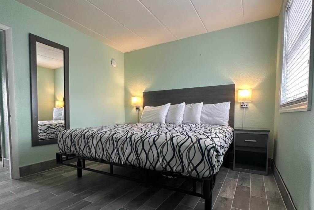 um quarto de hotel com uma cama e um espelho em Royal Canadian Motel em Wildwood