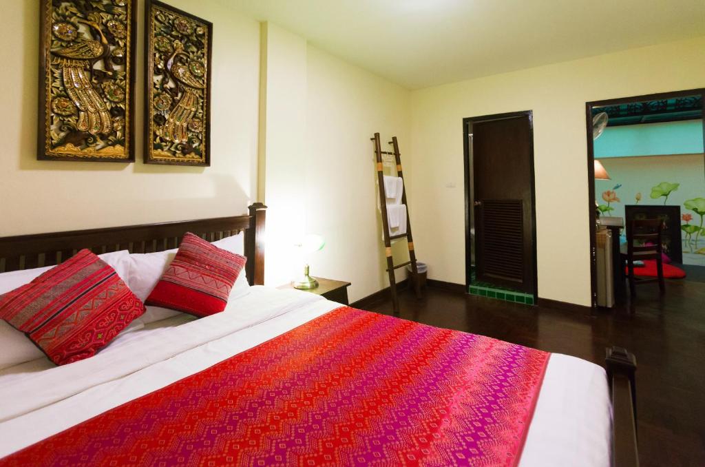 A decorated bedroom with a patterned bedspread and adjoining room.