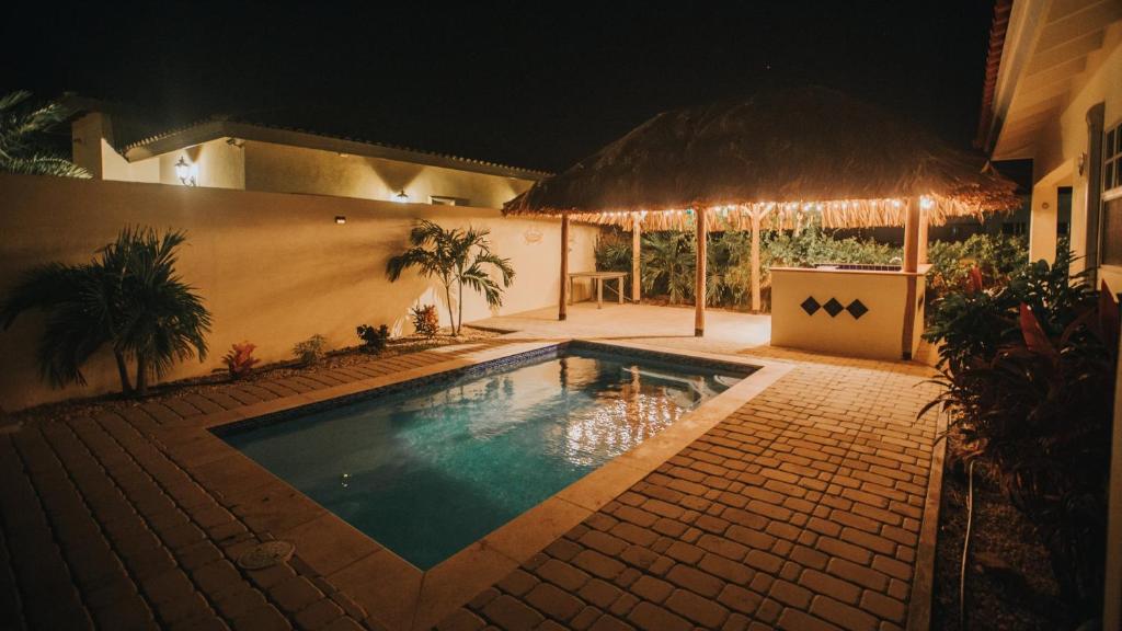 a swimming pool in front of a house at night at Dushi Villa in Palm-Eagle Beach