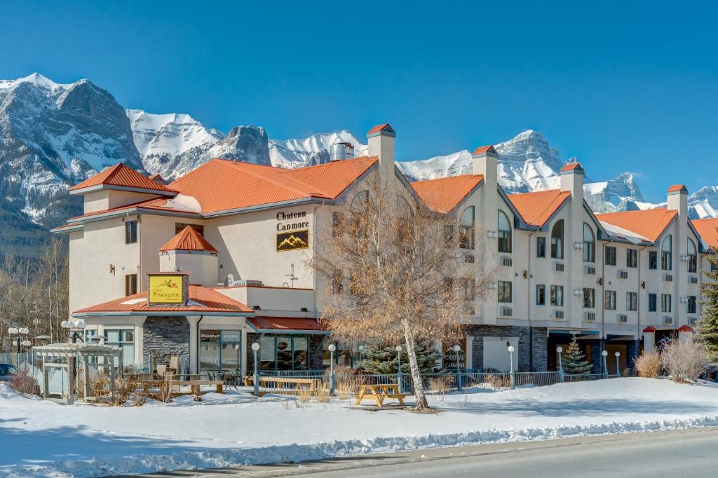 a hotel with snowy mountains in the background at Chateau Canmore in Canmore