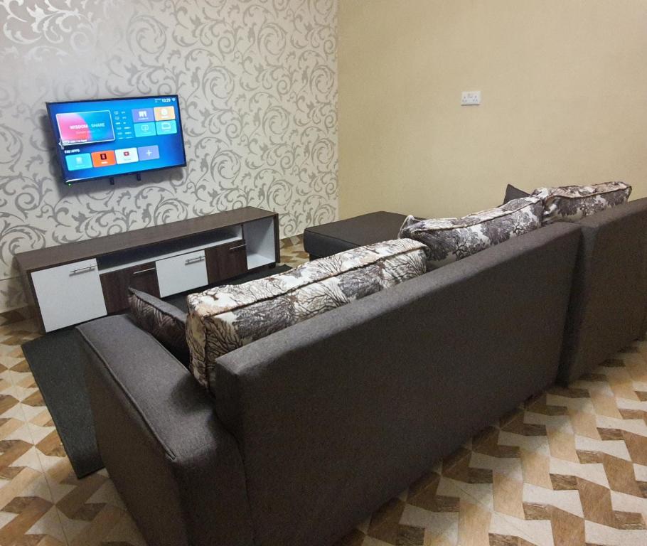 two couches in a room with a tv on a wall at Pearl suites in Bungoma