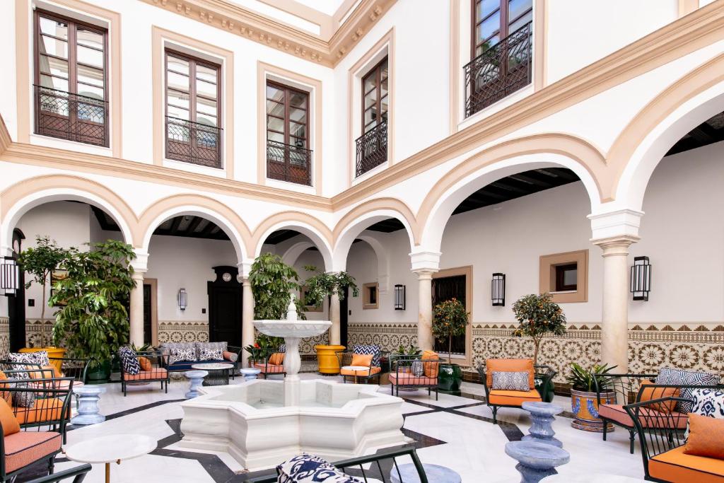 eine Lobby mit einem Brunnen, Stühlen und Tischen in der Unterkunft Hotel Casa Palacio Don Ramón in Sevilla
