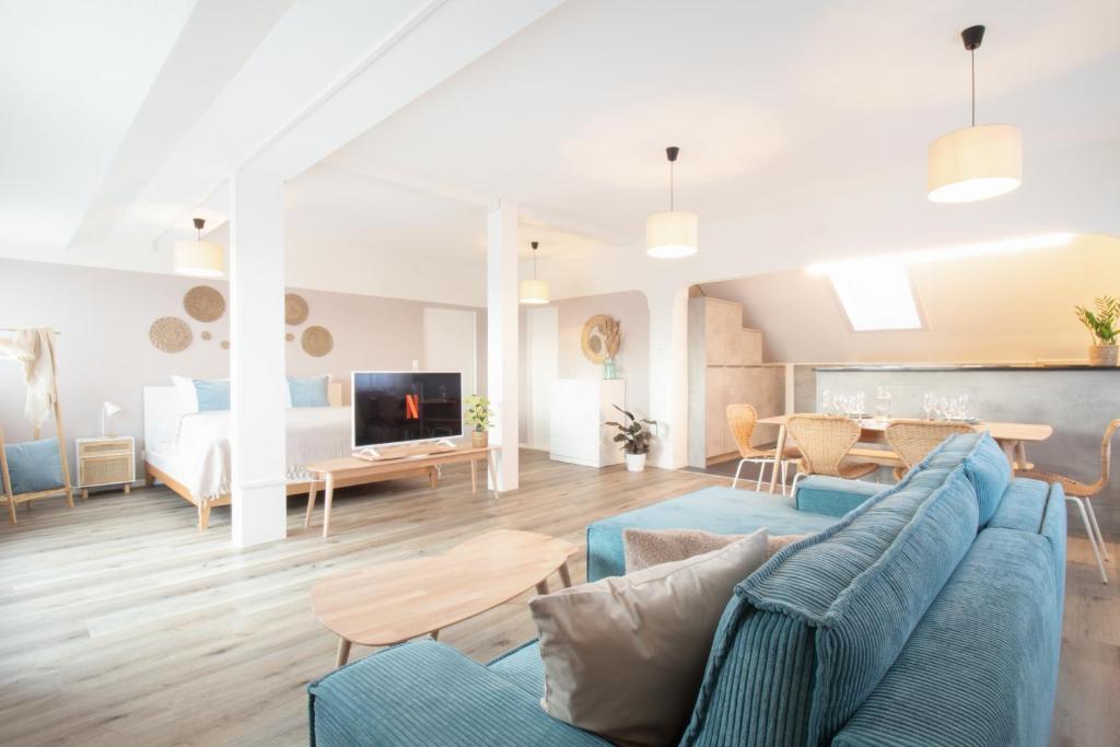 a living room and dining room with a blue couch at Löwe Apartments "Blau" Neuhausen am Rheinfall in Neuhausen am Rheinfall