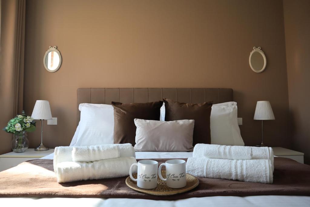Una cama con dos tazas y toallas. en A Casa Tua, en Bolonia