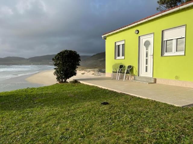 una casa verde con 2 sillas frente a la playa en Apartamento Playa de Lires, en Cee