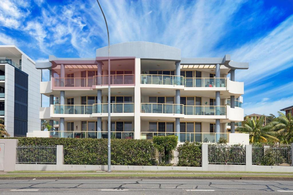 a tall white building with balconies on a street at Riviera 306 in Port Macquarie