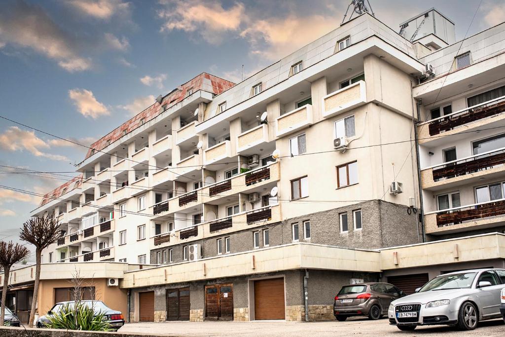 un gran edificio blanco con coches estacionados frente a él en Явор en Tryavna