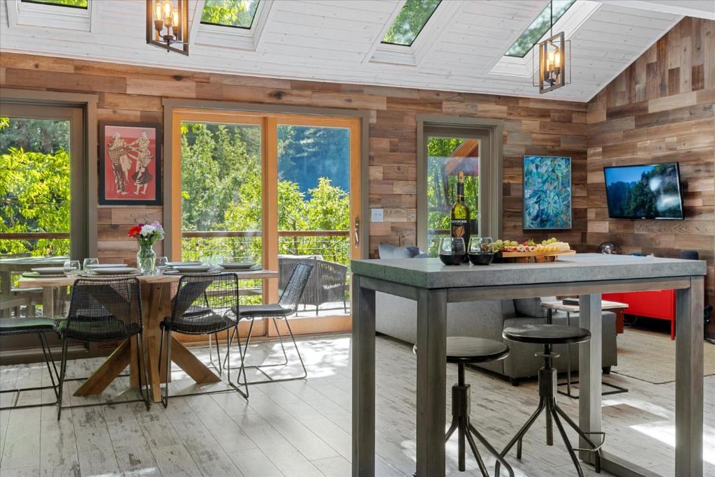 a living room with a table and chairs and windows at Sydneys River Retreat in Guerneville